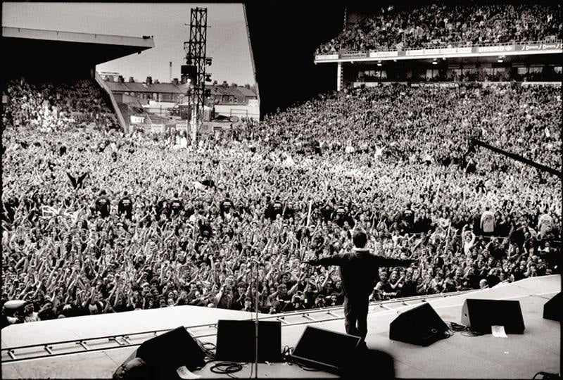 Oasis, Noel Gallagher arms outstretched, Manchester, April 1996 by Jill Furmanovsky